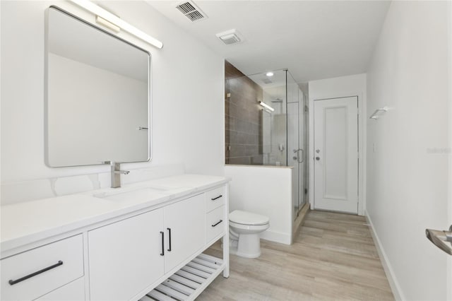 bathroom with hardwood / wood-style flooring, toilet, vanity, and a shower with shower door