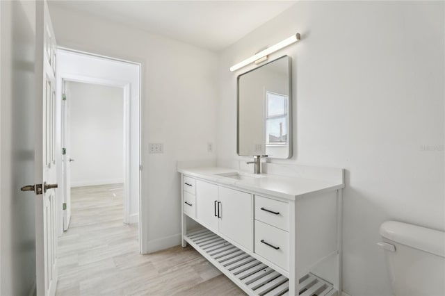 bathroom with toilet, vanity, and hardwood / wood-style floors