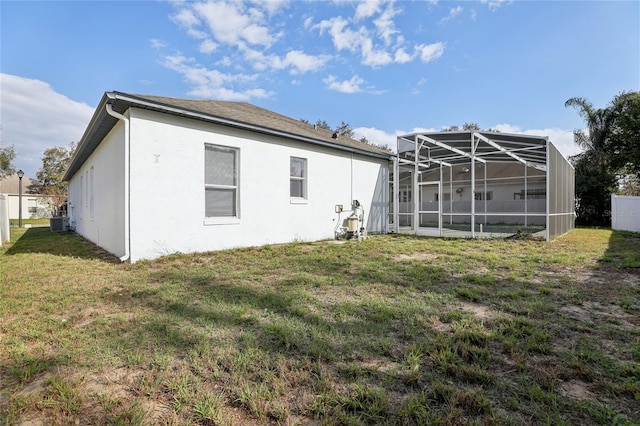rear view of property featuring central AC unit, a yard, and a lanai