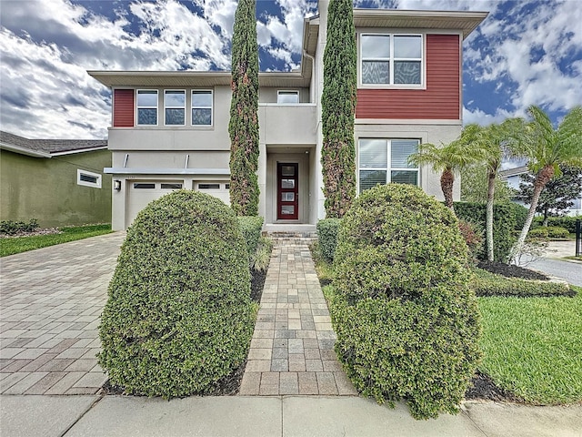 view of front of house featuring a garage, decorative driveway, and stucco siding