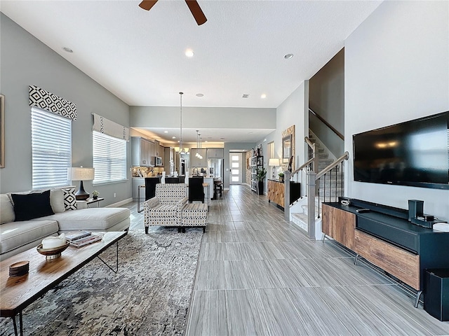 living area featuring stairs, ceiling fan, a wealth of natural light, and recessed lighting