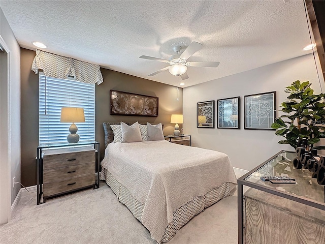 bedroom featuring light carpet, a textured ceiling, baseboards, and a ceiling fan