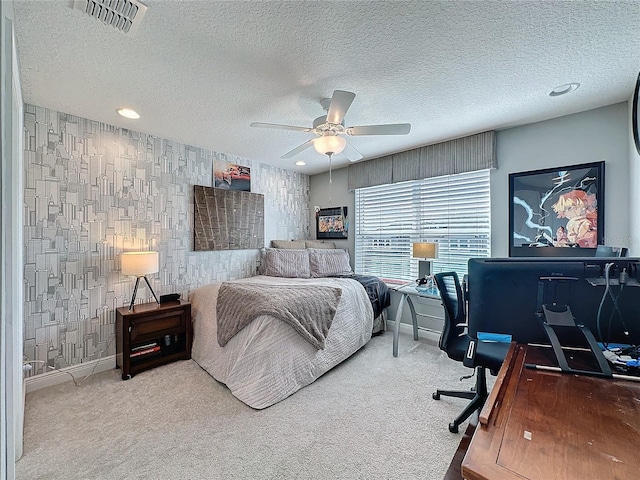 bedroom with a textured ceiling, carpet floors, visible vents, baseboards, and wallpapered walls