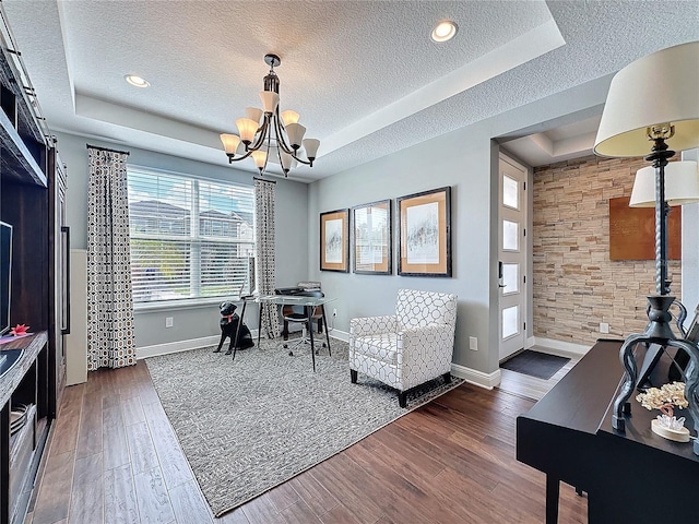 office featuring dark wood-style floors, a textured ceiling, a raised ceiling, and a notable chandelier