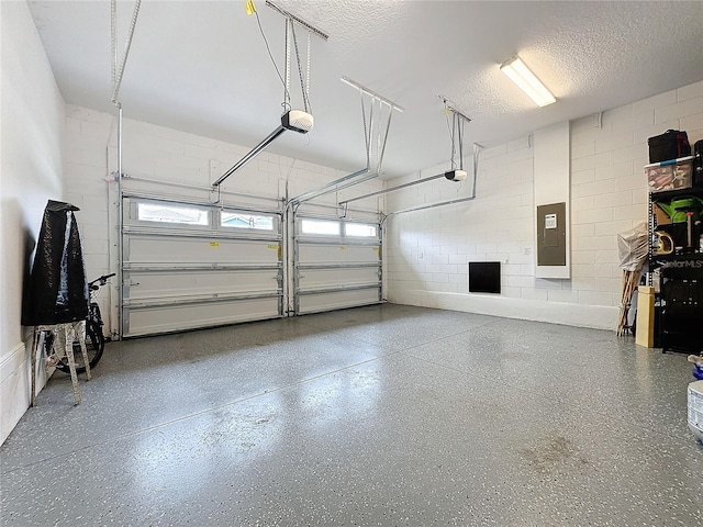 garage featuring concrete block wall, electric panel, and a garage door opener