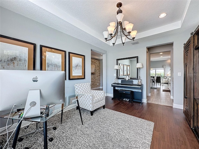 office area featuring a tray ceiling, a barn door, and dark wood finished floors