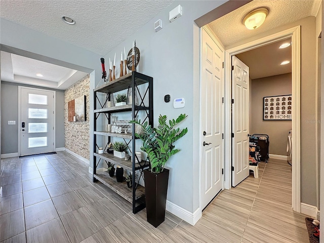 corridor with light tile patterned flooring, a textured ceiling, and baseboards