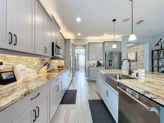 kitchen featuring visible vents, gray cabinets, pendant lighting, and stainless steel appliances