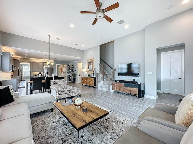 living area with stairs, recessed lighting, visible vents, baseboards, and ceiling fan with notable chandelier