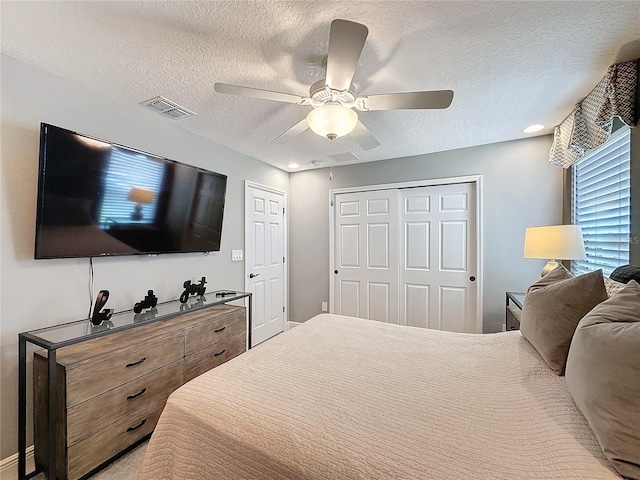 bedroom featuring a closet, visible vents, ceiling fan, and a textured ceiling