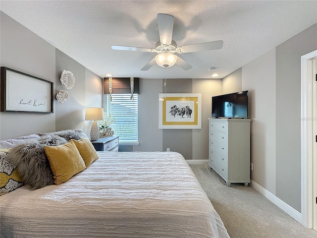 bedroom featuring ceiling fan, baseboards, a textured ceiling, and light colored carpet