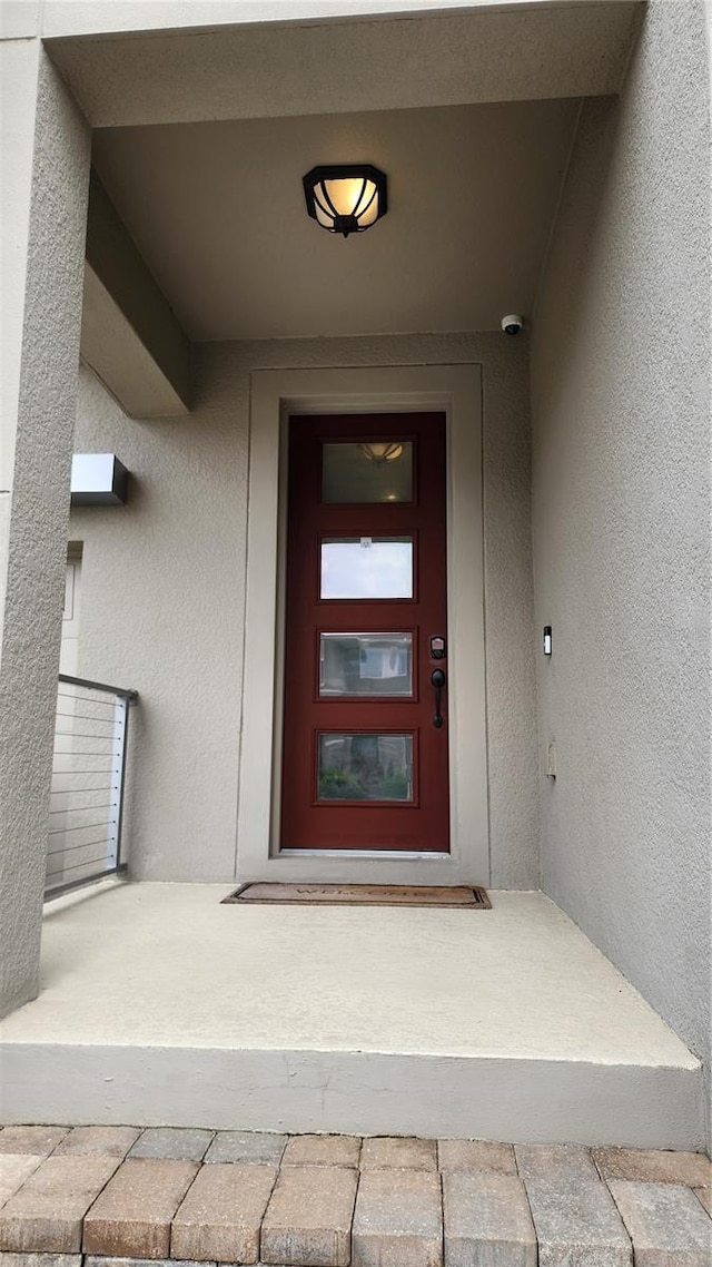 doorway to property featuring stucco siding