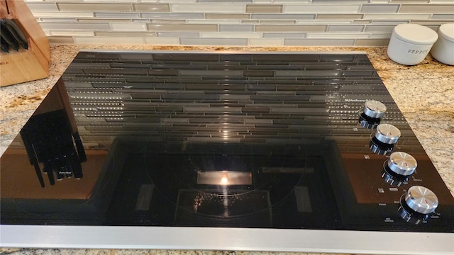 details featuring black electric cooktop and light stone countertops