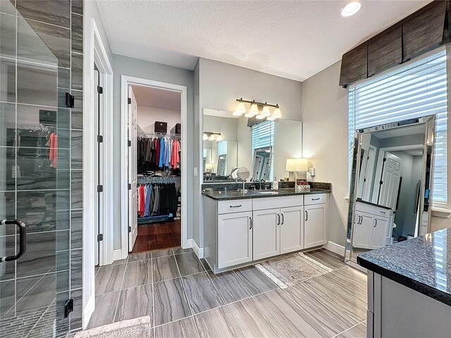 16150 Parkwyn St, Winter Garden, FL 34787 - bathroom with a textured ceiling, a stall shower, baseboards, vanity, and a walk in closet