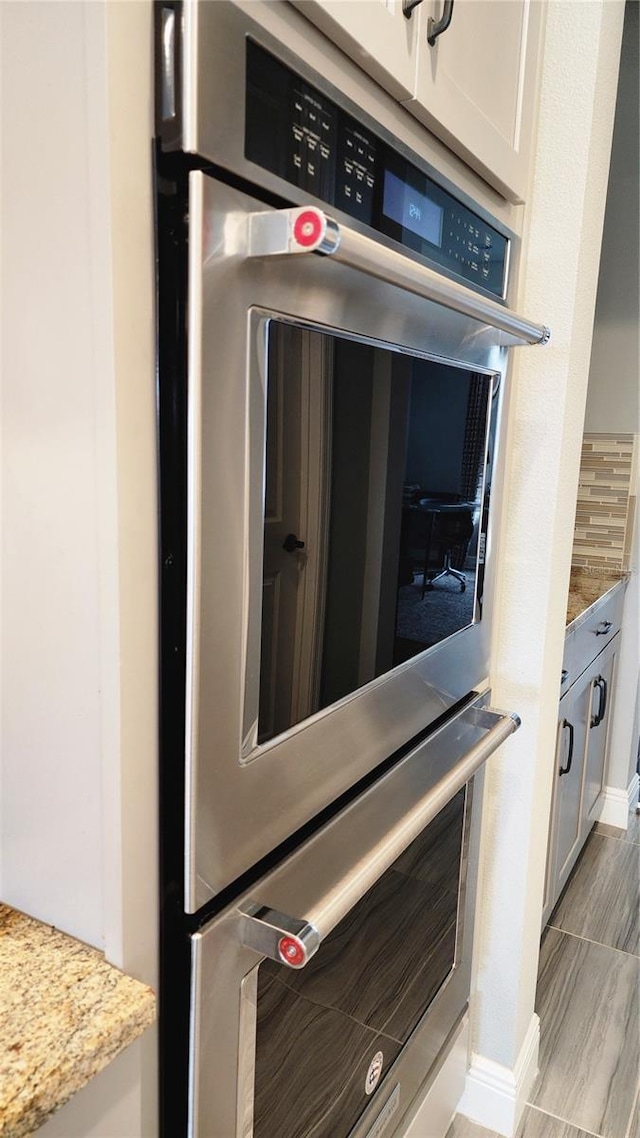 16150 Parkwyn St, Winter Garden, FL 34787 - interior details with white cabinets, light wood finished floors, baseboards, light stone countertops, and double oven