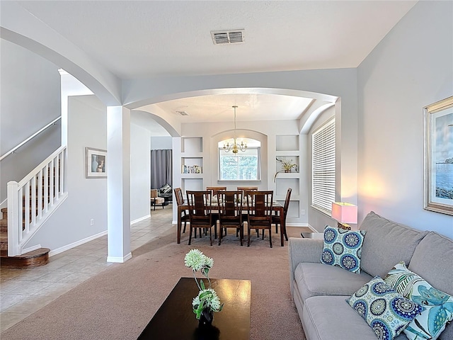 131 Stella Pass, Davenport, FL 33837 - tiled living room featuring stairway, carpet floors, built in features, arched walkways, and baseboards