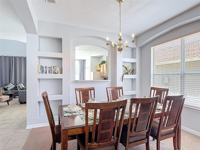 131 Stella Pass, Davenport, FL 33837 - dining space with built in features, a textured ceiling, arched walkways, a chandelier, and baseboards