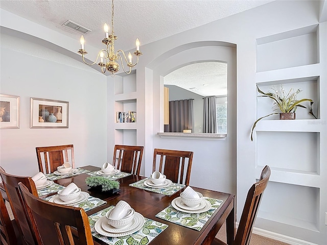 131 Stella Pass, Davenport, FL 33837 - dining area featuring a textured ceiling, arched walkways, built in shelves, and a chandelier