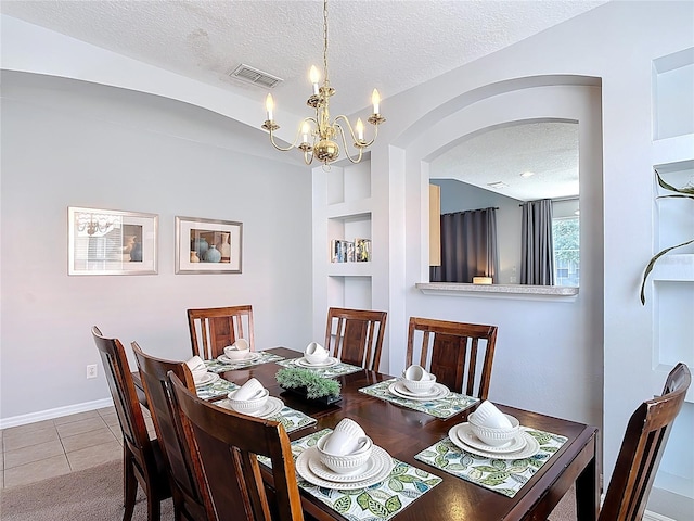 131 Stella Pass, Davenport, FL 33837 - dining area with a textured ceiling, built in features, arched walkways, a chandelier, and tile patterned flooring