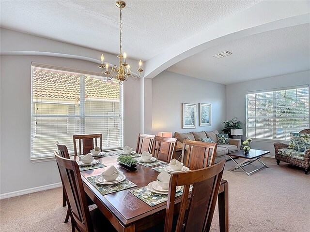 131 Stella Pass, Davenport, FL 33837 - carpeted dining space with arched walkways, a chandelier, a textured ceiling, and baseboards