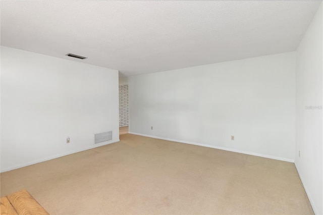 spare room with baseboards, visible vents, a textured ceiling, and light colored carpet