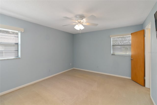 empty room with light carpet, baseboards, and a ceiling fan