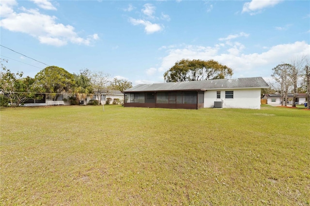 rear view of house with a sunroom, a yard, and central AC unit