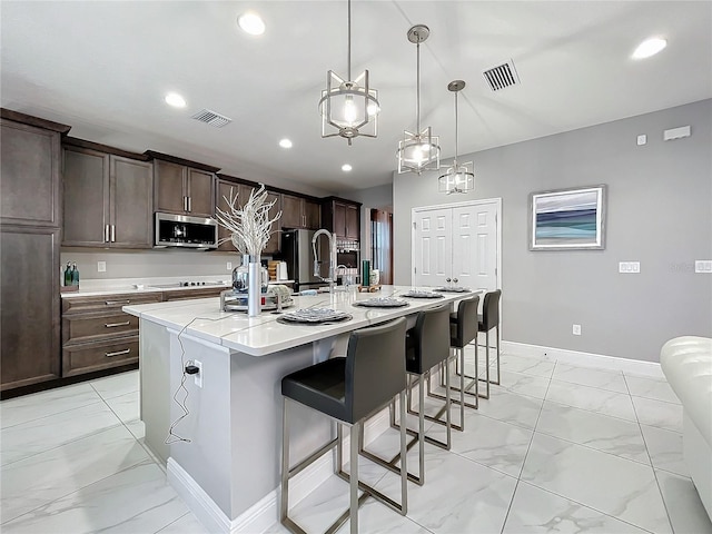 kitchen featuring marble finish floor, stainless steel appliances, visible vents, and dark brown cabinetry