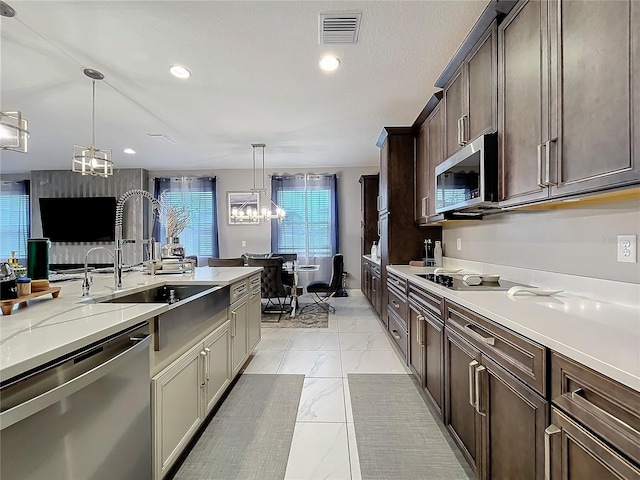 kitchen with appliances with stainless steel finishes, a sink, visible vents, and a notable chandelier