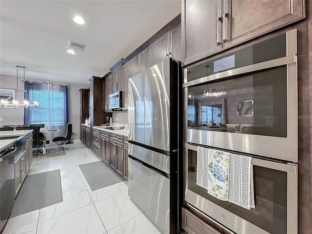 kitchen featuring dark brown cabinetry, visible vents, marble finish floor, stainless steel appliances, and a chandelier