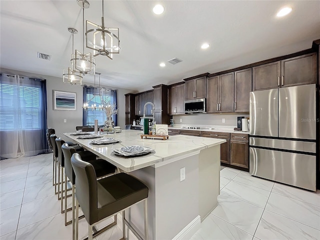 kitchen with marble finish floor, stainless steel appliances, an island with sink, and visible vents