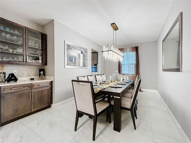 dining room with marble finish floor, baseboards, and an inviting chandelier