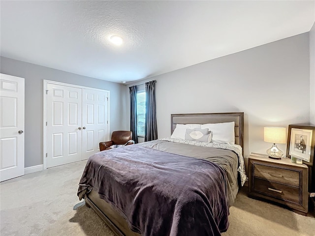 bedroom with baseboards, a closet, and light colored carpet