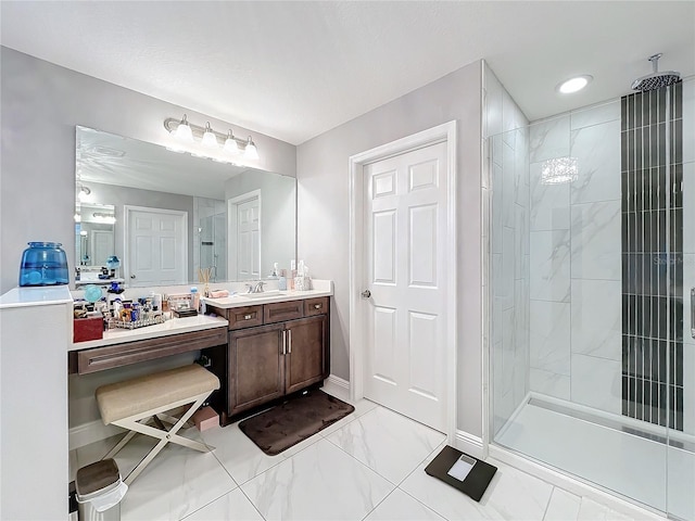 bathroom featuring marble finish floor, tiled shower, vanity, and baseboards