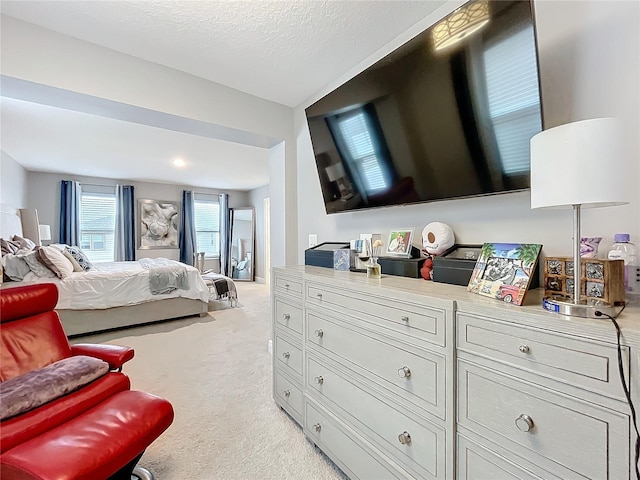 bedroom with a textured ceiling and light colored carpet