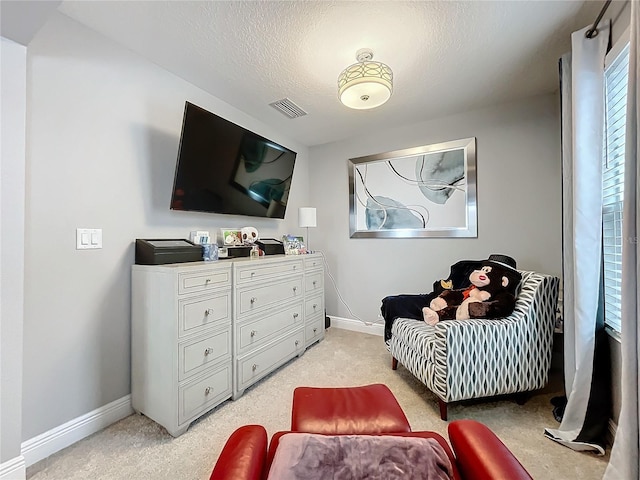 living area featuring baseboards, visible vents, a textured ceiling, and light colored carpet