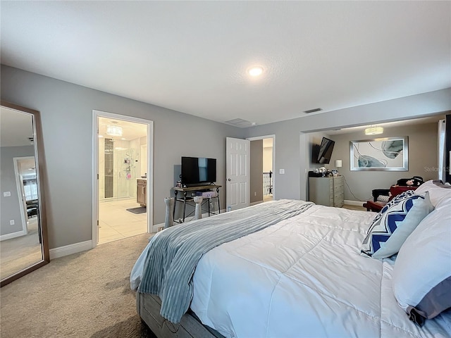 carpeted bedroom with ensuite bath, baseboards, and visible vents