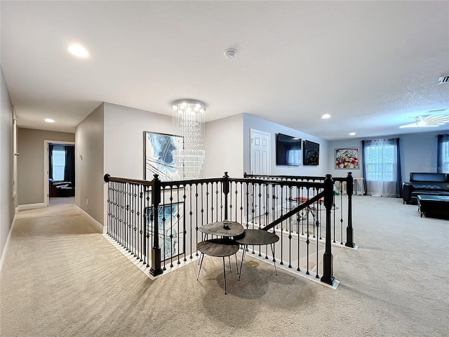 corridor with recessed lighting, carpet flooring, an upstairs landing, a chandelier, and baseboards