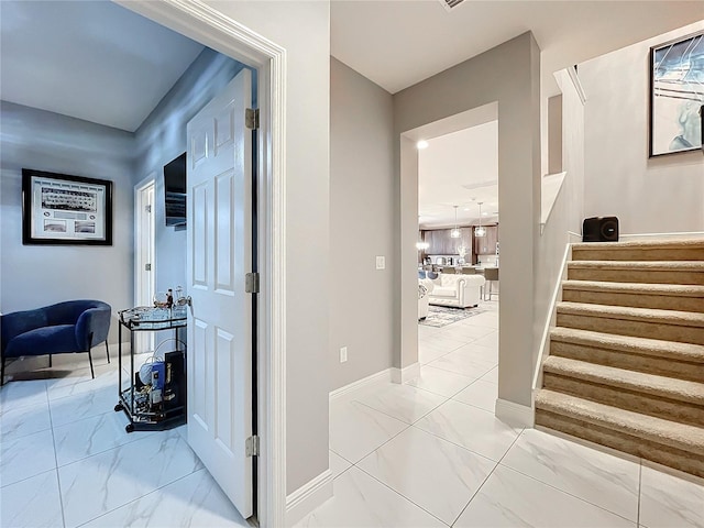 corridor with marble finish floor, stairs, and baseboards