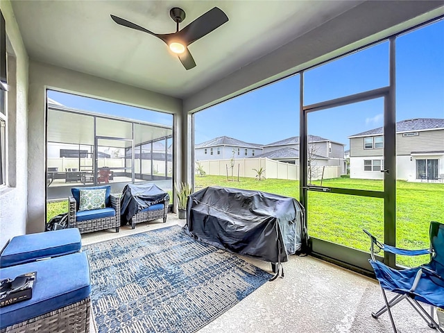 sunroom / solarium with a residential view and ceiling fan