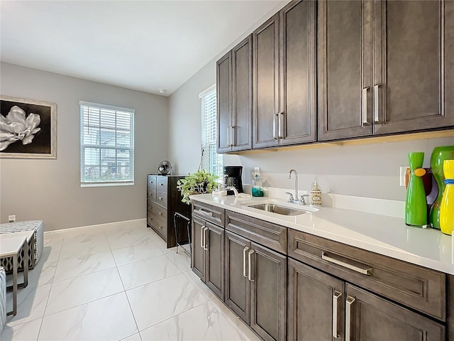 kitchen with marble finish floor, light countertops, a sink, and dark brown cabinets