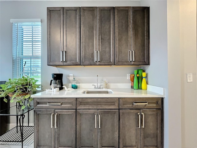 kitchen with dark brown cabinets, a sink, and light countertops