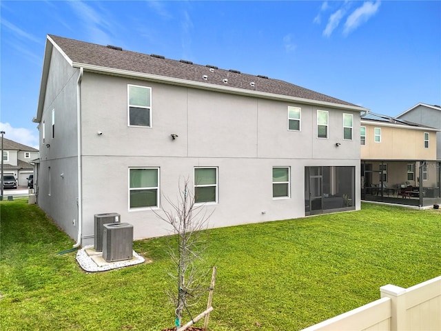 rear view of property with a yard, central air condition unit, a sunroom, and stucco siding