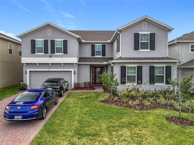 traditional home featuring a garage, a front lawn, decorative driveway, and stucco siding