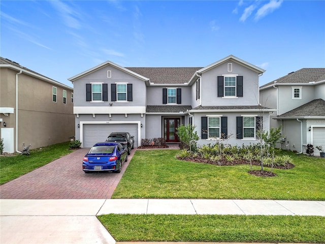 traditional-style house with a garage, a front yard, decorative driveway, and stucco siding