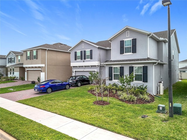 traditional-style home with a garage, roof with shingles, decorative driveway, a front lawn, and stucco siding