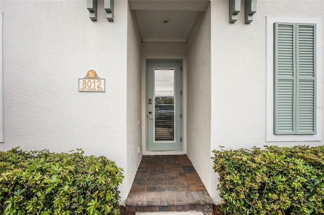 doorway to property featuring stucco siding