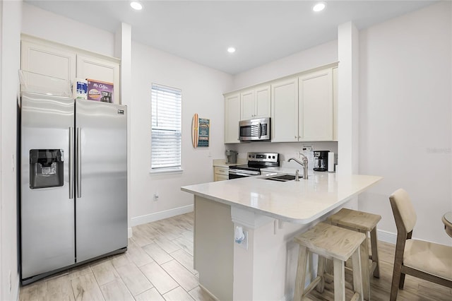 8012 Lost Shaker Ln, Kissimmee, FL 34747 - kitchen featuring a breakfast bar, a sink, stainless steel appliances, a peninsula, and light countertops