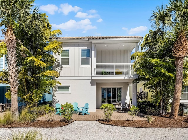 8012 Lost Shaker Ln, Kissimmee, FL 34747 - back of house with a tiled roof, a balcony, a patio area, and board and batten siding