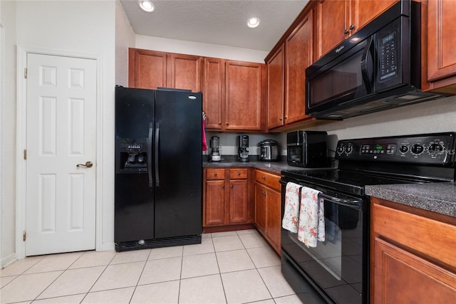 kitchen featuring a textured ceiling, light tile patterned flooring, black appliances, brown cabinetry, and dark countertops